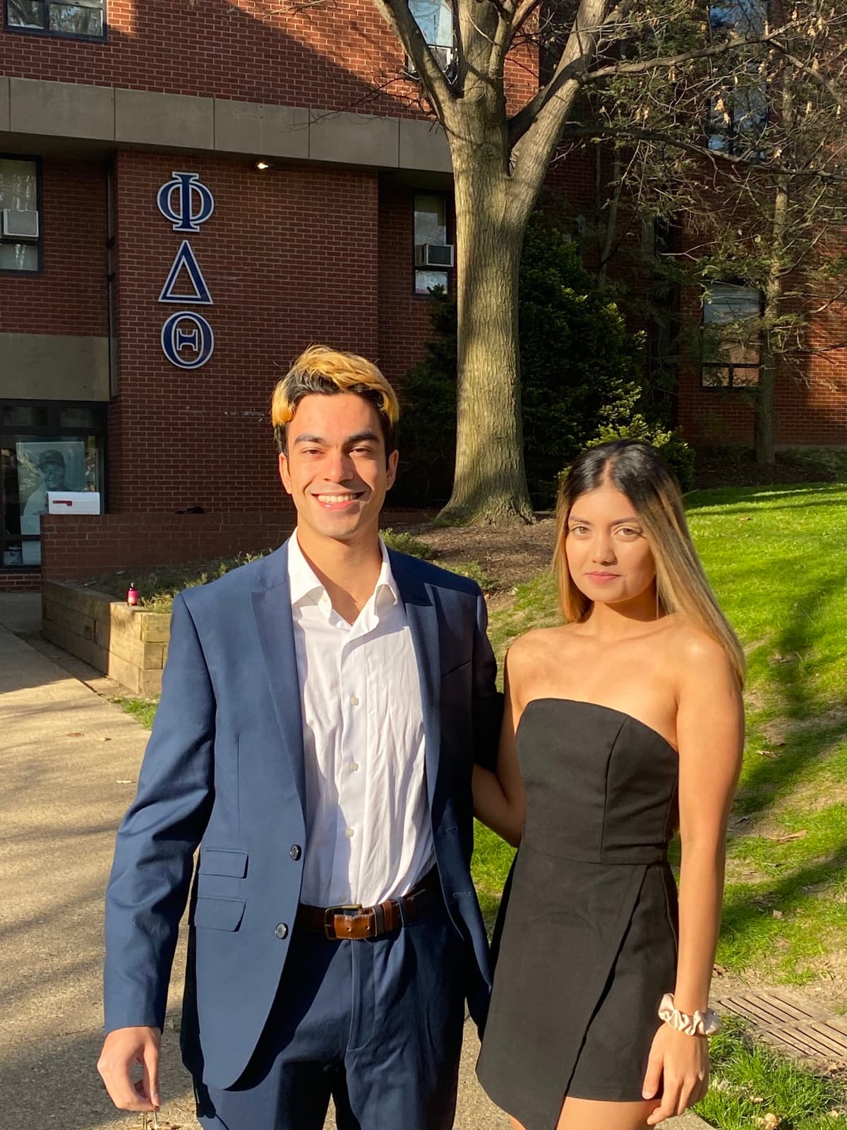 Krati and Shaan dressed for a celebration outside a brick building